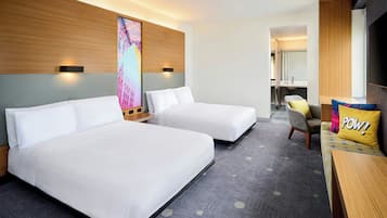 Habitación de hotel con dos camas, un sofá, un escritorio y un espejo grande.