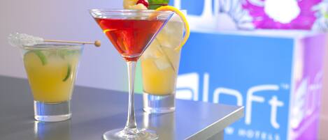Deux cocktails sur le comptoir d’un bar, avec une enseigne d’hôtel en arrière-plan.