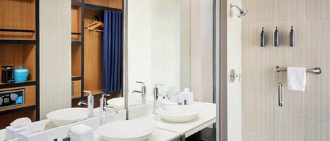A modern bathroom with two sinks, a large mirror, and a shower area.