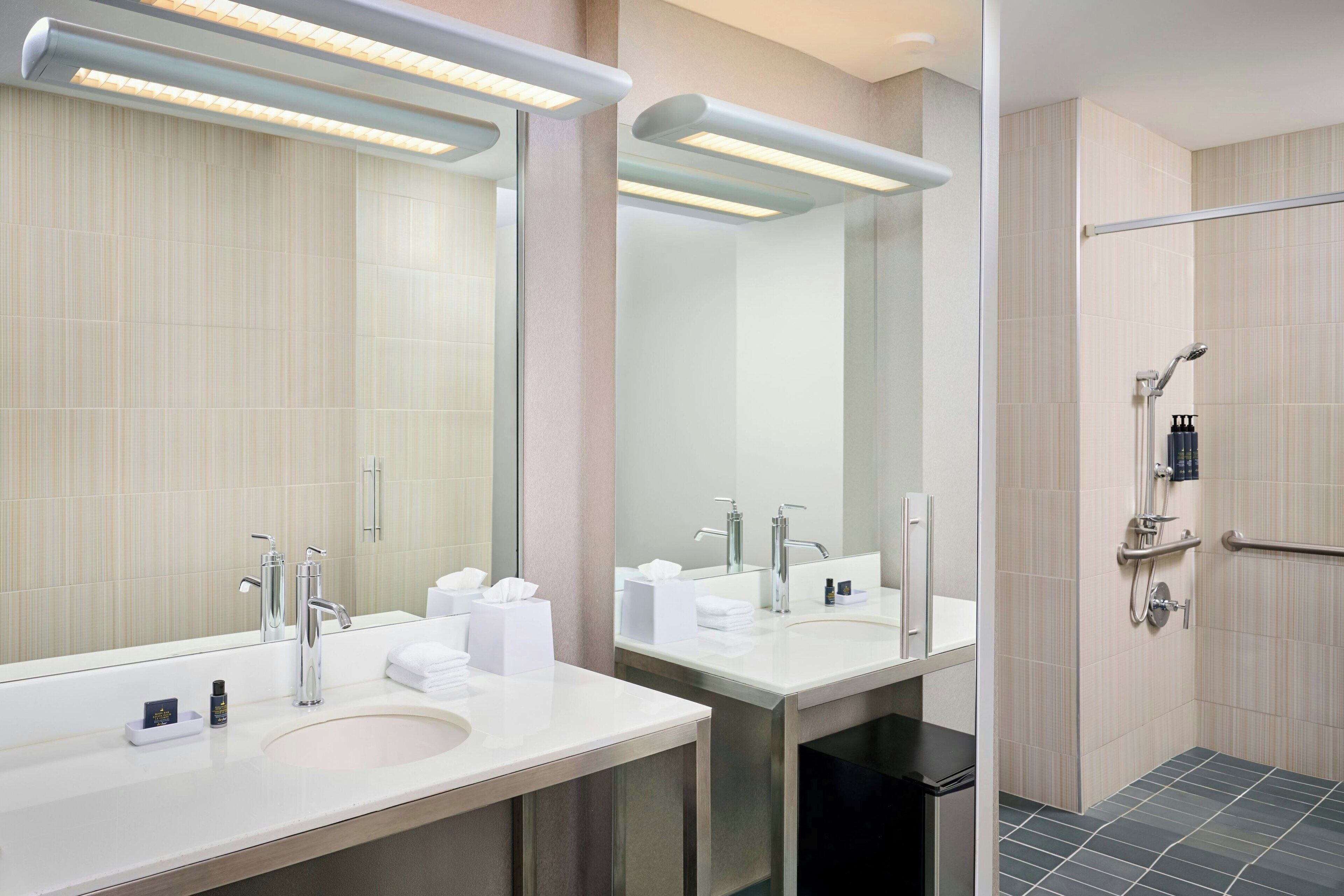Une salle de bain moderne avec deux lavabos, un grand miroir et un espace douche.