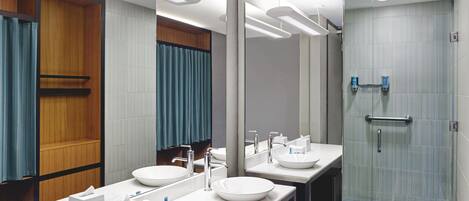 A modern bathroom with two sinks, a large mirror, and a glass shower enclosure.