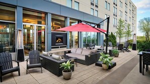 An outdoor patio with seating, a fireplace, and potted plants. - Aloft by Marriott Montreal Airport (Dorval)