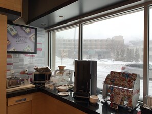 A breakfast area with a view of a snowy parking lot and buildings outside. - Aloft by Marriott Montreal Airport (Dorval)