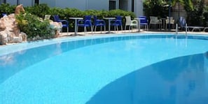 Una piscina al aire libre, sombrillas, sillones reclinables de piscina
