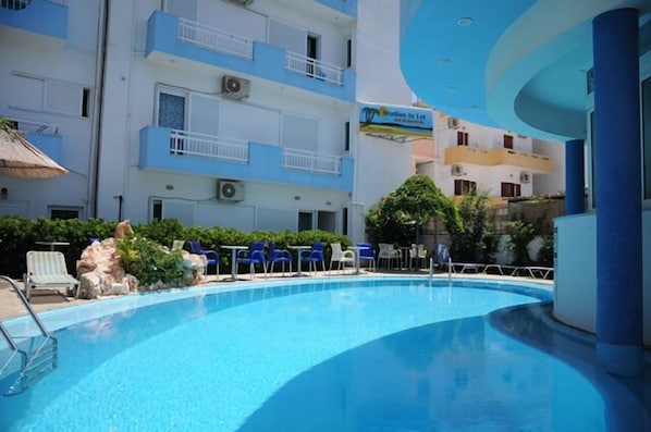 Una piscina al aire libre, sombrillas, sillones reclinables de piscina