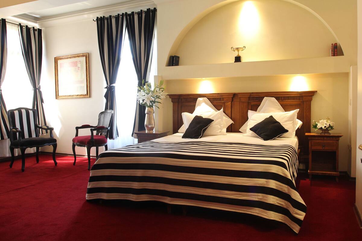 Une chambre d’hôtel avec un grand lit, deux chaises, une petite table et une table de chevet.