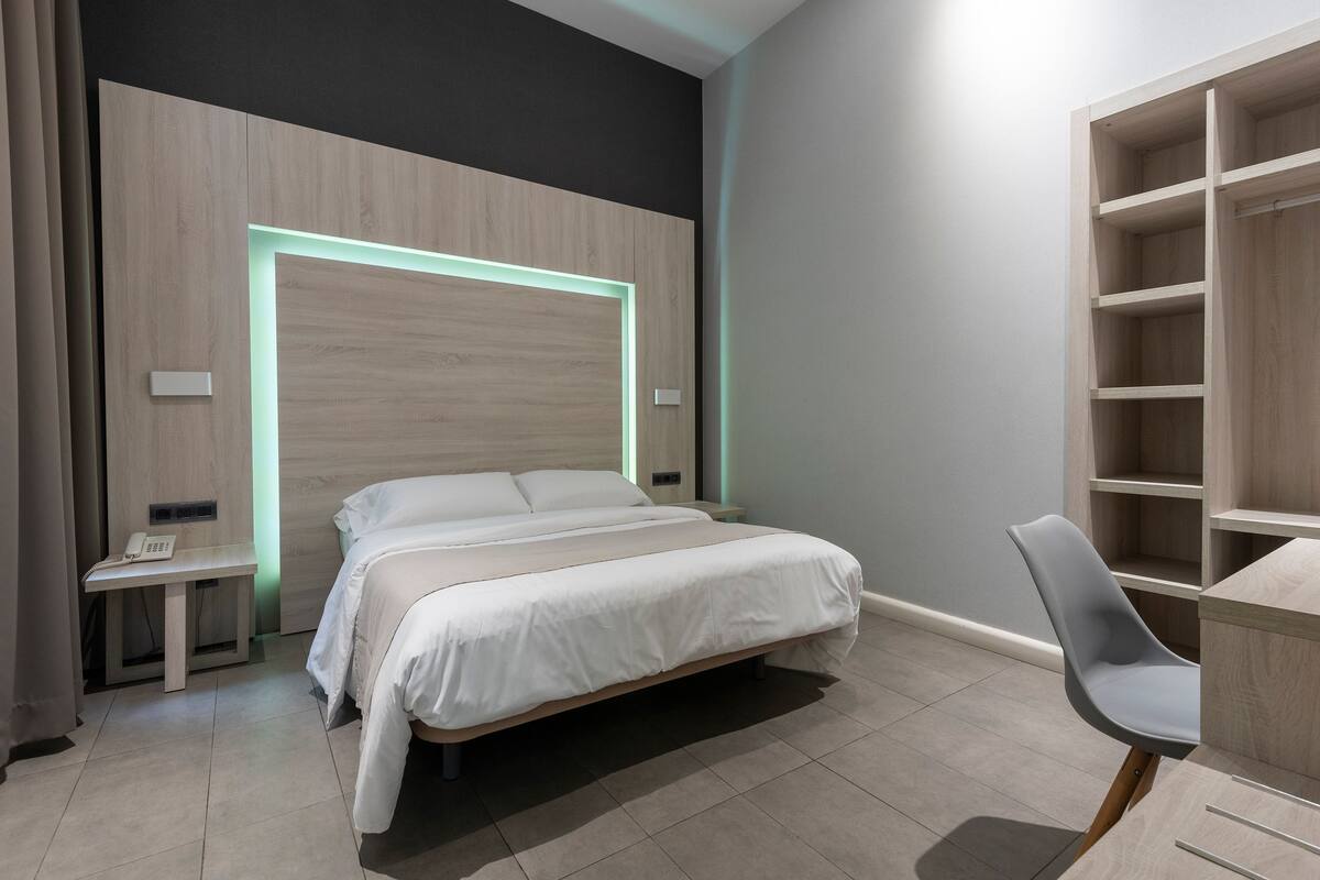 Een moderne slaapkamer met een bed, nachtkastje en een stoel.