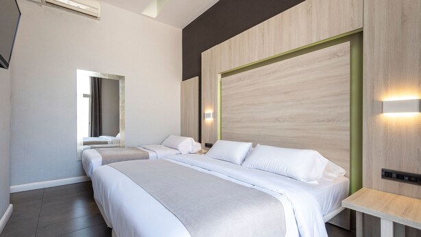 A modern hotel room with a large bed, a bedside table, a mirror, and a wall-mounted light fixture. - Plaza Goya Rooms (Barcelona)