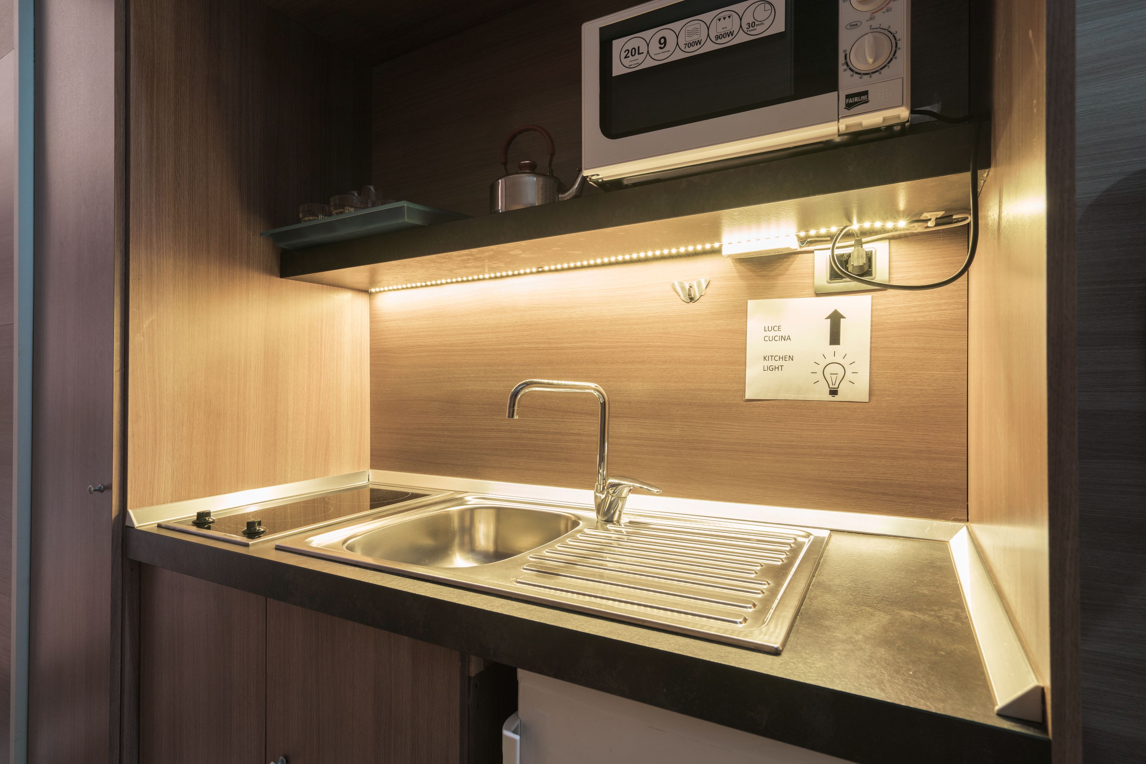 A compact kitchen with a double sink, a microwave, and a built-in oven.