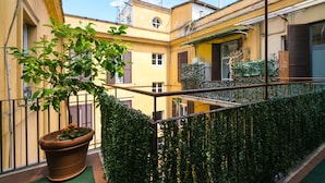 A courtyard with a potted plant, a metal railing, and a building with a yellow facade. - Residence Europa (Rome)