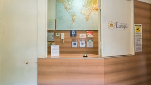 A reception desk with a world map, a bell icon, and various informational signs. - Residence Europa (Rome)