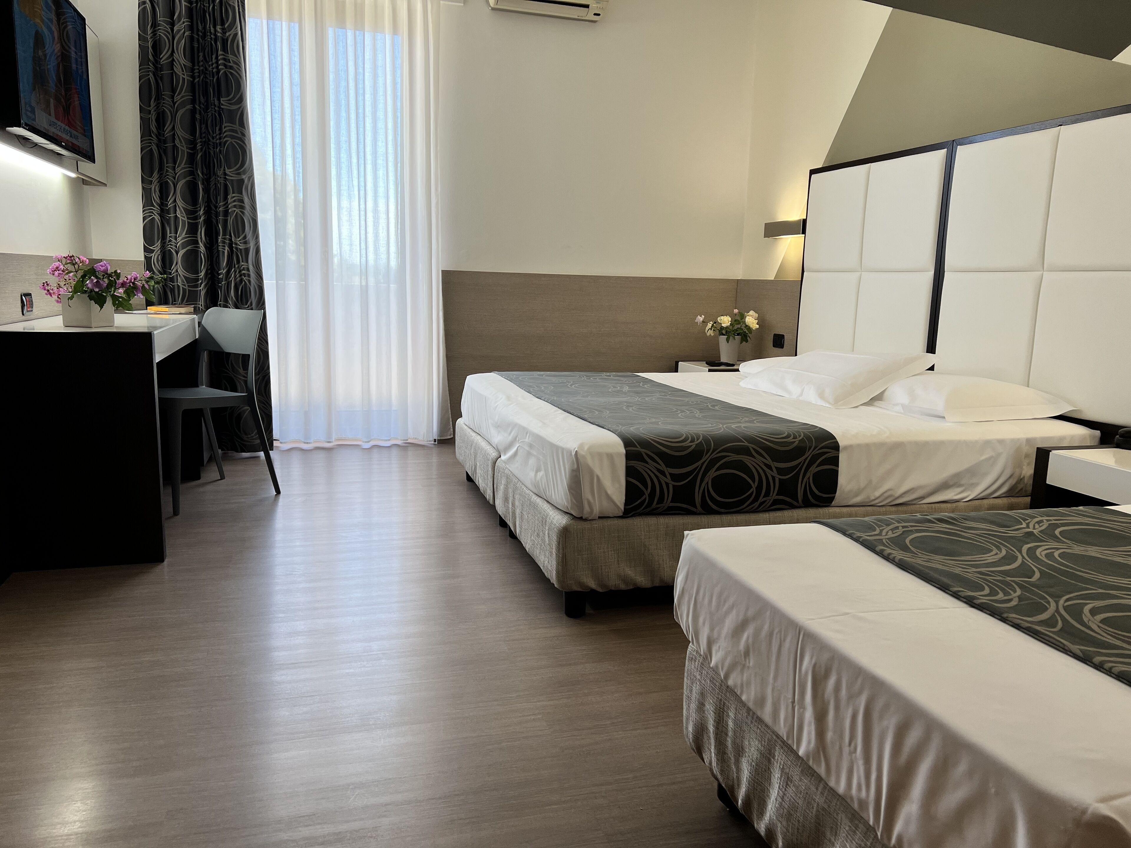 Habitación de hotel con dos camas, un escritorio y una silla.