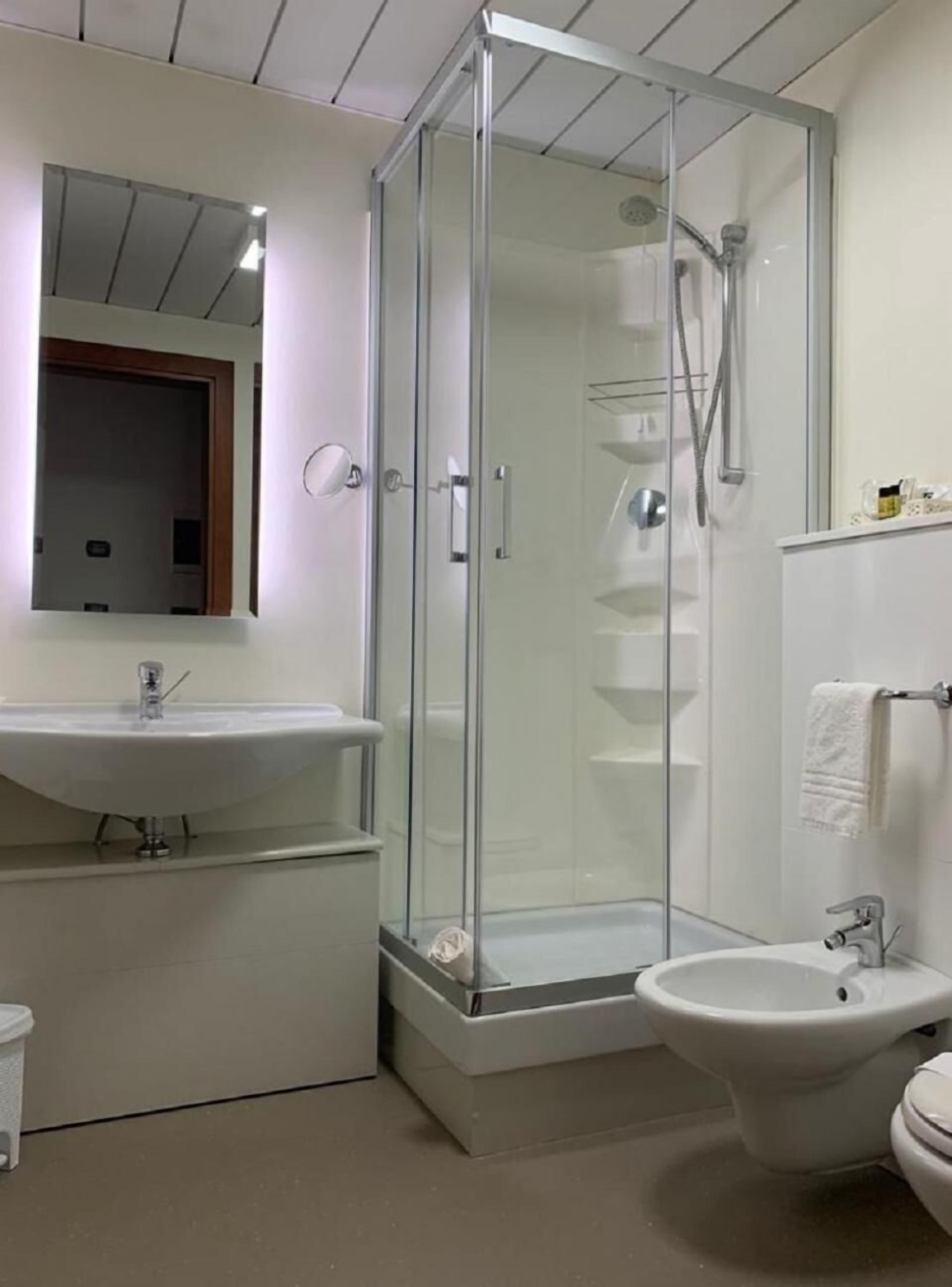 A modern bathroom with a glass-enclosed shower, a sink, and a bidet.