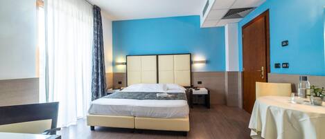 A hotel room with a bed, bedside tables, a desk, and a table with a tablecloth.
