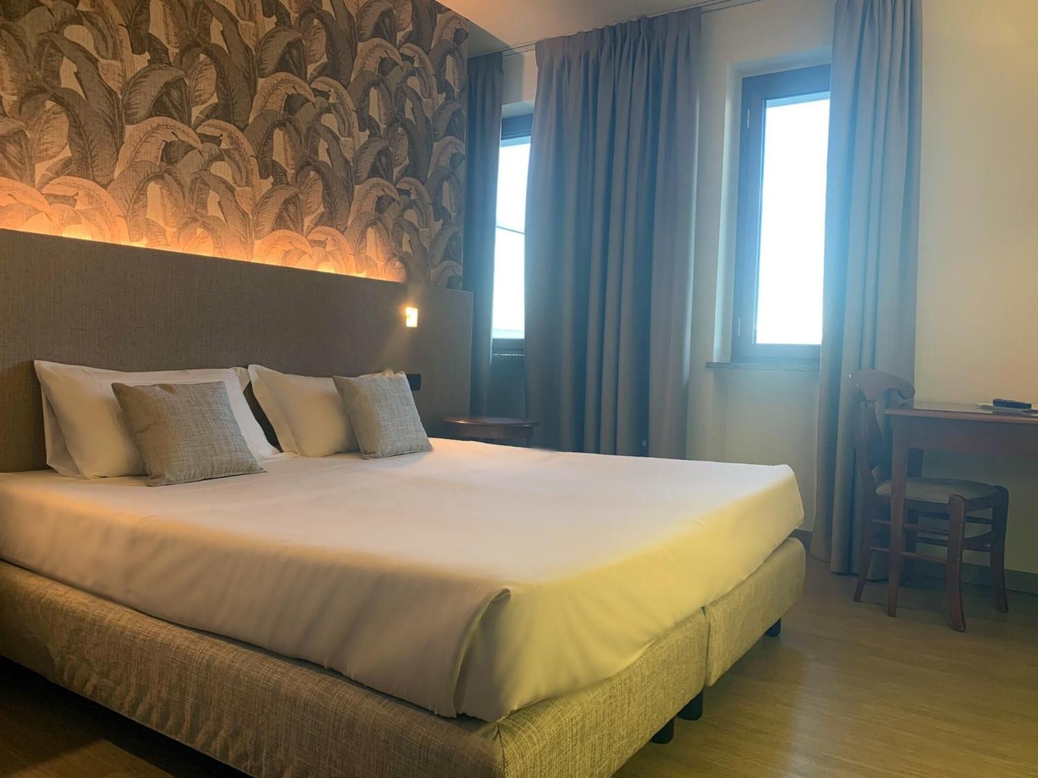 Una habitación de hotel con una cama grande, un escritorio y una silla.