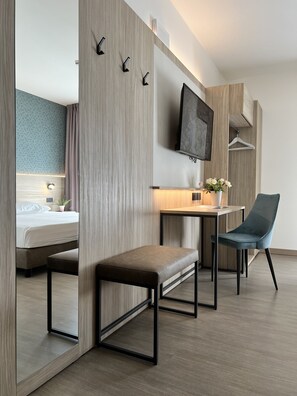 A modern hotel room with a bed, a desk, a chair, and a TV mounted on the wall. - Hotel Gardenia (Romano Canavese)