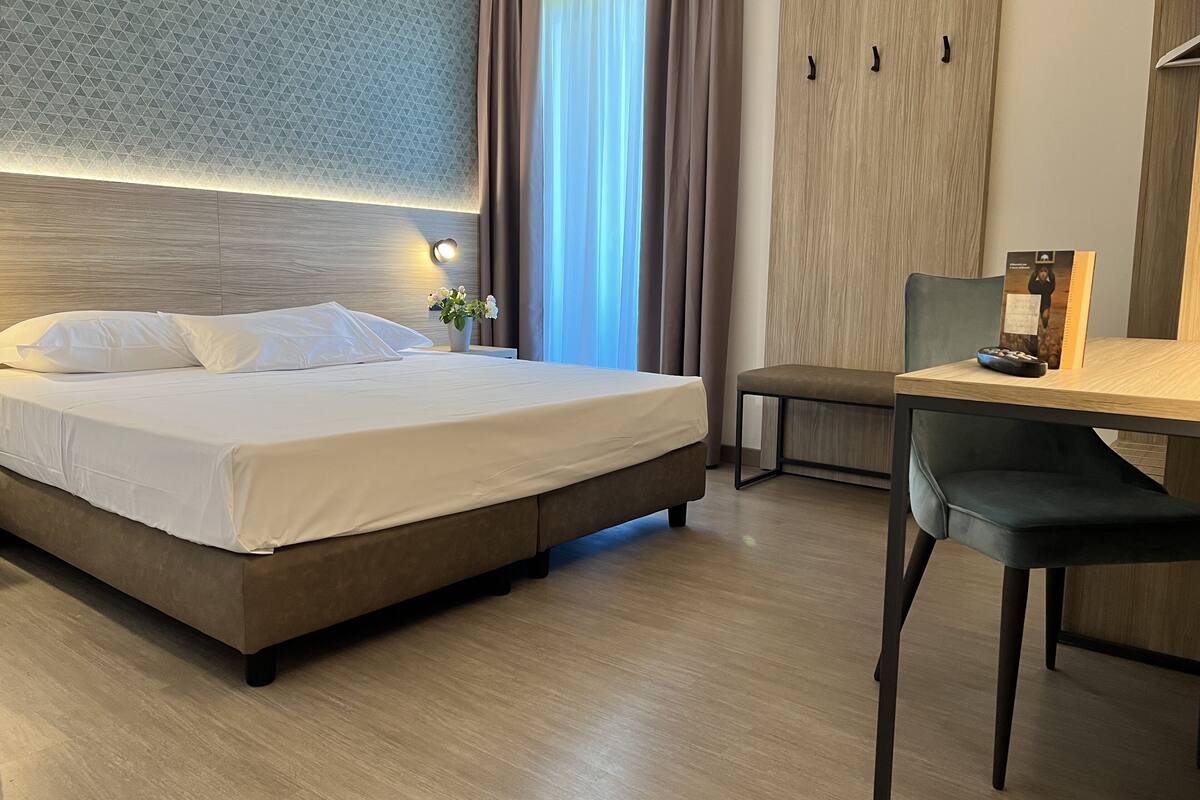 Une chambre d’hôtel avec un lit, un bureau et une chaise.