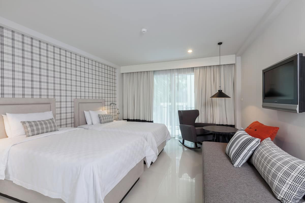 Una habitación de hotel moderna con una cama grande, un sofá, un escritorio y un televisor.