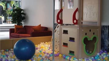 Un área de juegos con piscina de pelotas, una estructura de escalada y un sofá de cuadros rojos y negros.