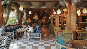 A restaurant with wooden furniture, checkered flooring, and hanging fans.