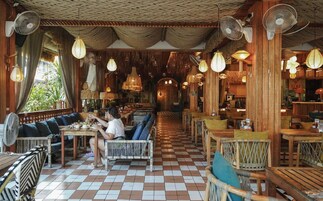 A restaurant with wooden furniture, checkered flooring, and hanging fans.