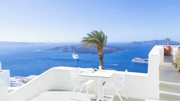 Relax in a serene outdoor seating area overlooking the Aegean Sea, surrounded by a palm tree and a modern building.