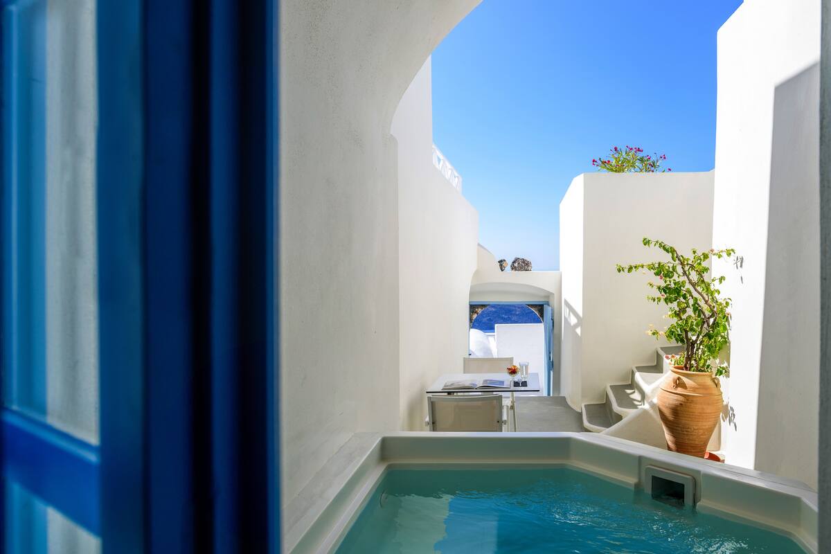 Un área de piscina estrecha con vistas a un edificio blanco y un cielo azul.