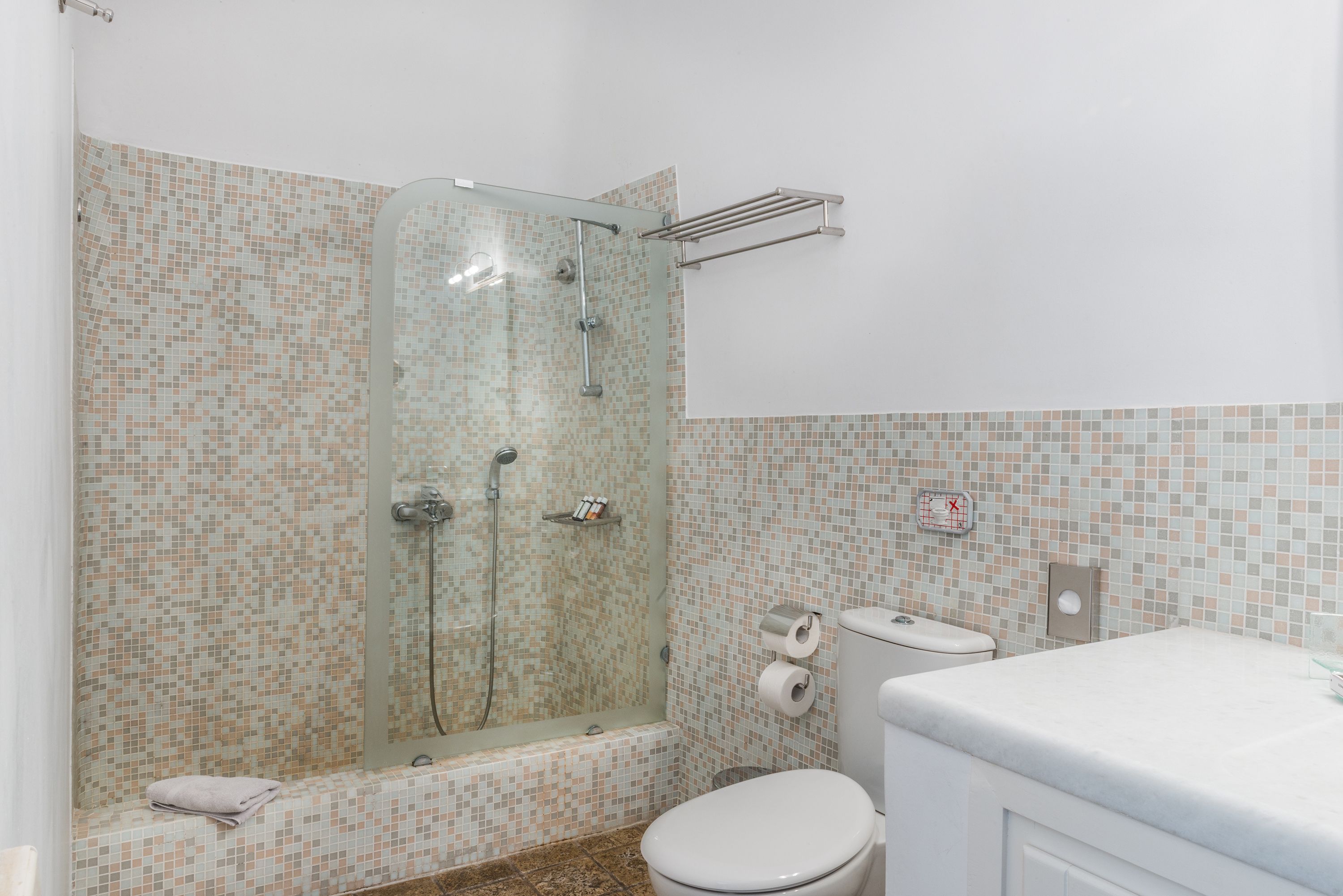A bathroom with a glass-enclosed shower, a toilet, and a sink.