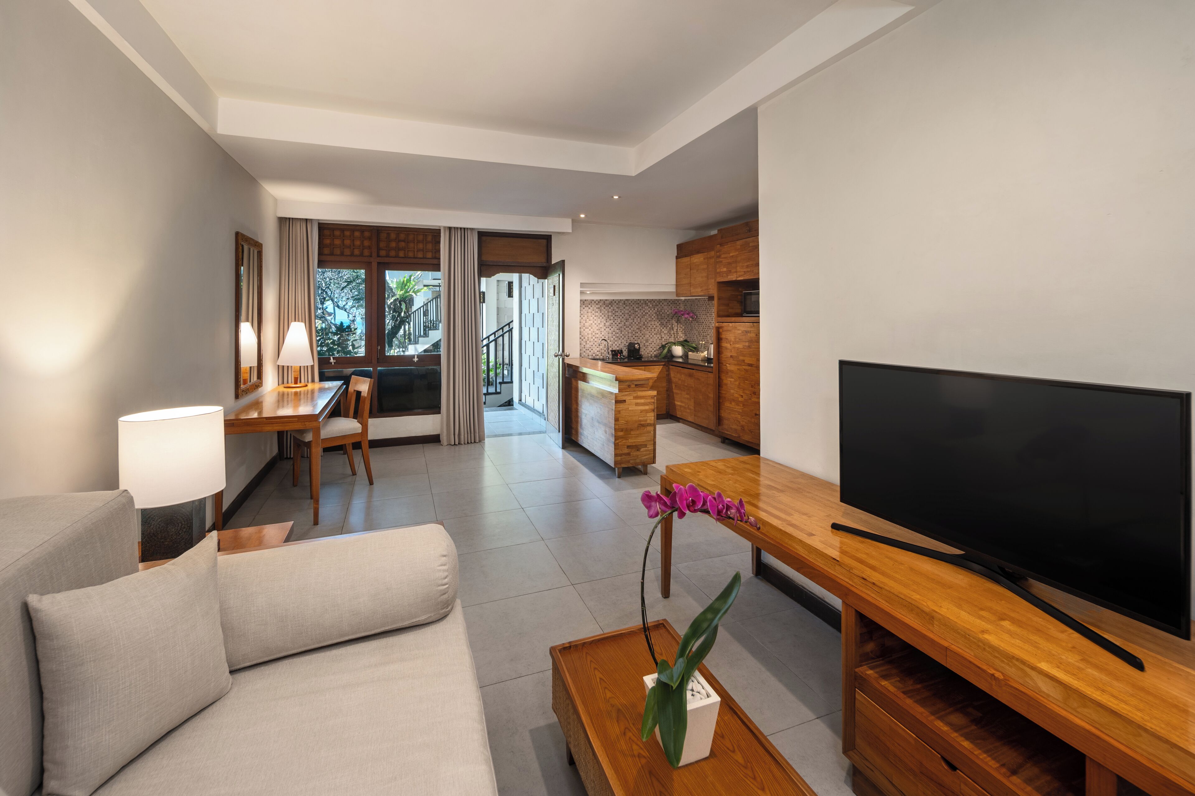 Una sala de estar moderna con sofá, mesa de centro, televisor y un comedor con mesa y sillas.