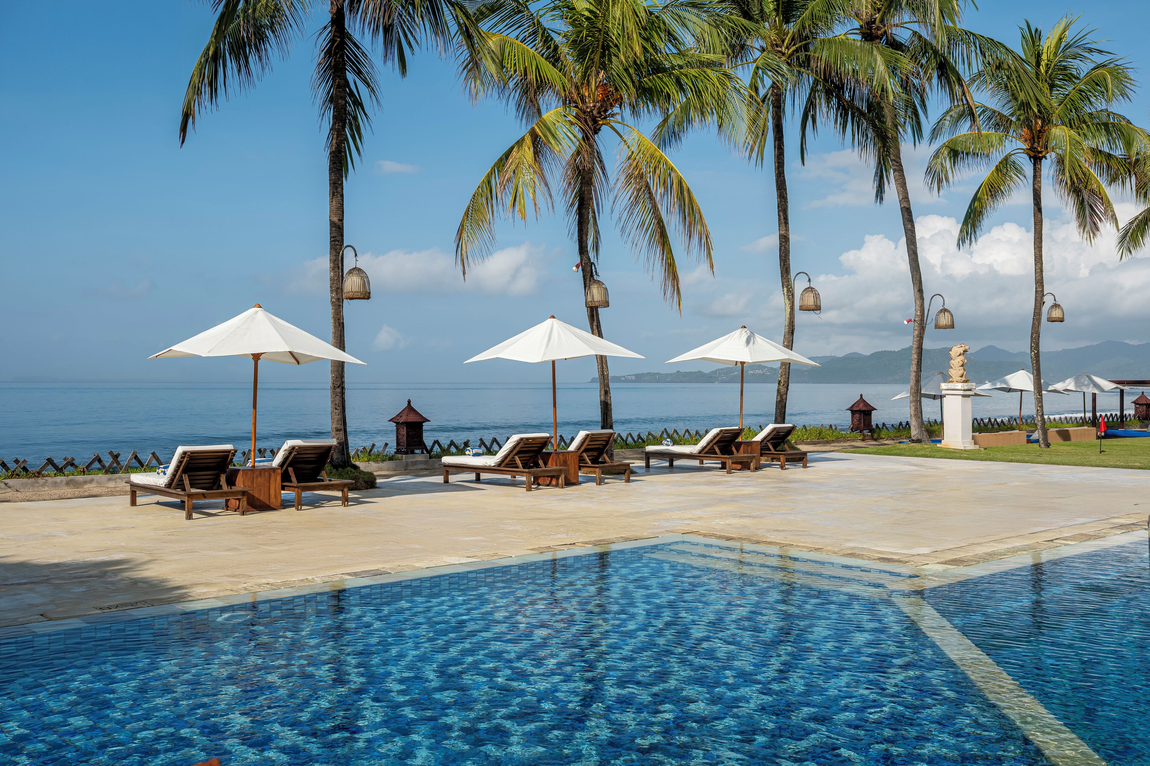 Una piscina al aire libre, sombrillas, sillones reclinables de piscina