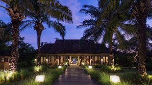 Un resort tropical con un sendero de madera que conduce a un edificio con techo de tejas.
