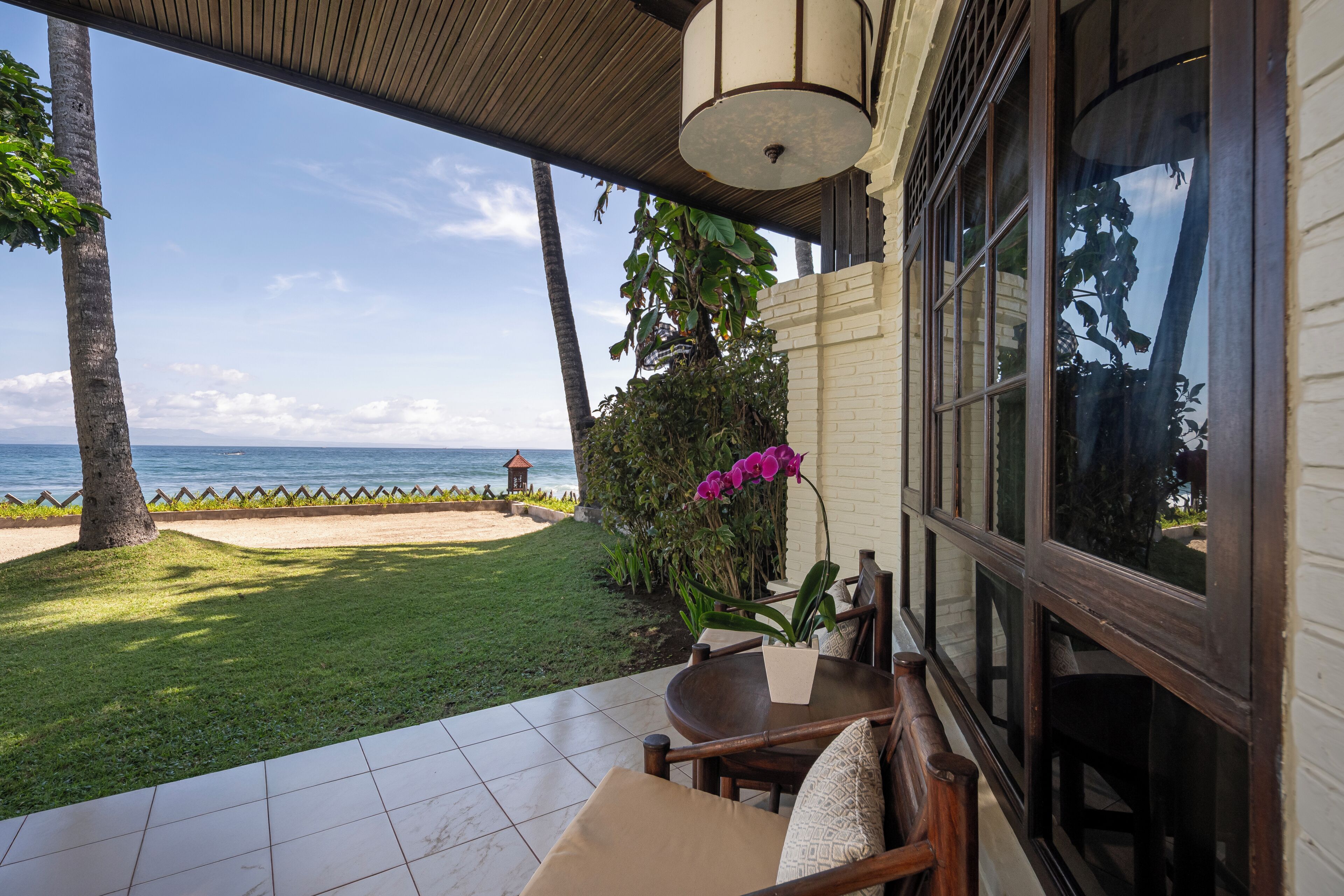 A patio with a view of the ocean, a wooden table, and a chair.
