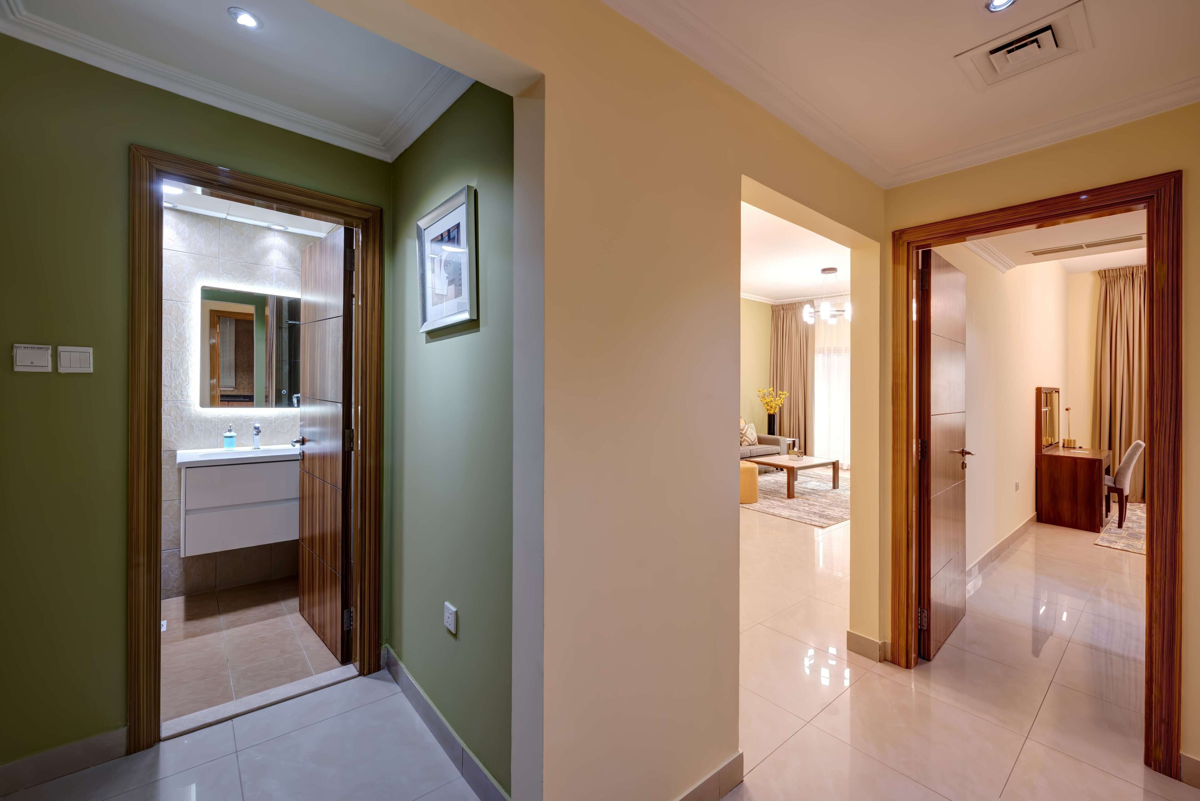 A hotel corridor with a bathroom, a living area, and a bedroom.