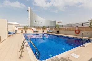 Una piscina de diseño moderno, rodeada de sillas de descanso y un cielo despejado.