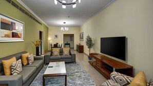 Een woonkamer met een bank, salontafel, televisie en decoratieve kussens.