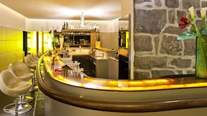 A bar area with a curved counter, bar stools, and a stone wall. - Hotel Marlena (Marlengo)