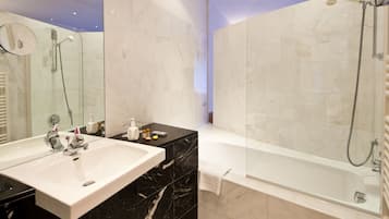 Un baño moderno con un lavamanos grande de color blanco, encimera de mármol negro y cabina de ducha separada.