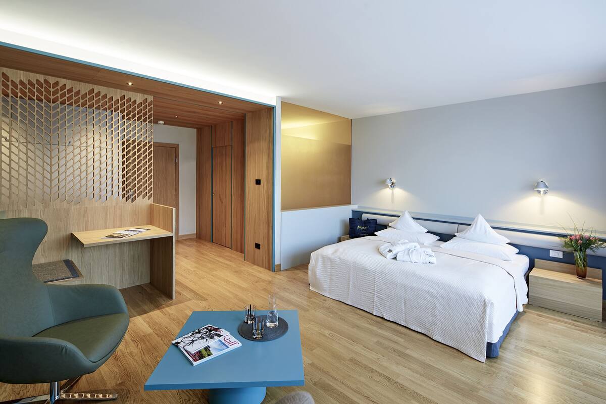 A modern hotel room with a bed, a desk, a chair, and a small table.