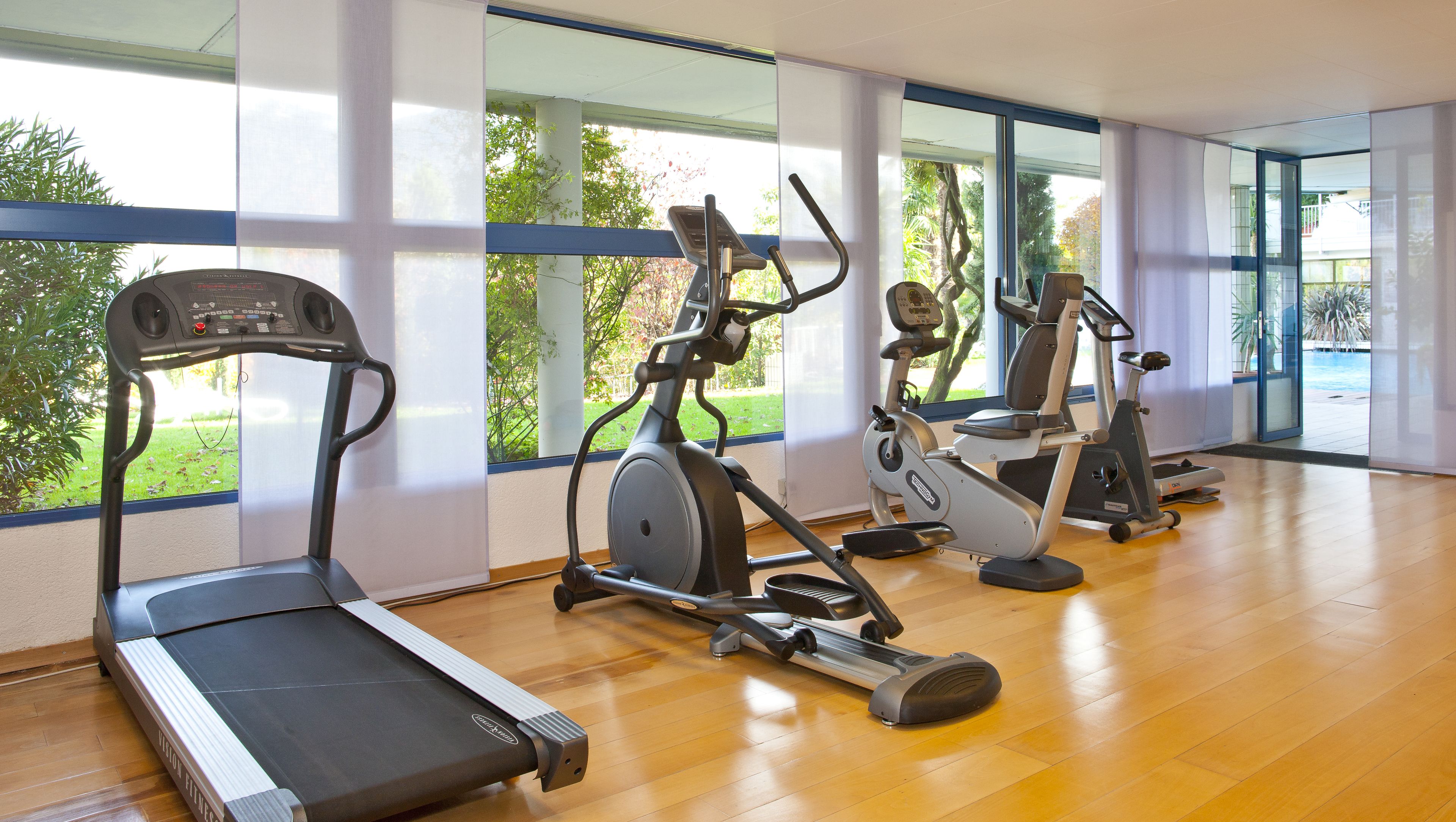 Un gimnasio con cinta de correr, elíptica y bicicleta estática.