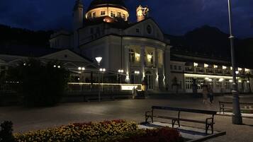 Ein historisches Gebäude mit Kuppel und klassischer Architektur, mit einem zentralen Innenhof, der eine Bank und Blumenbeete zeigt.