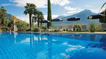 Una piscina techada, una piscina al aire libre, sombrillas