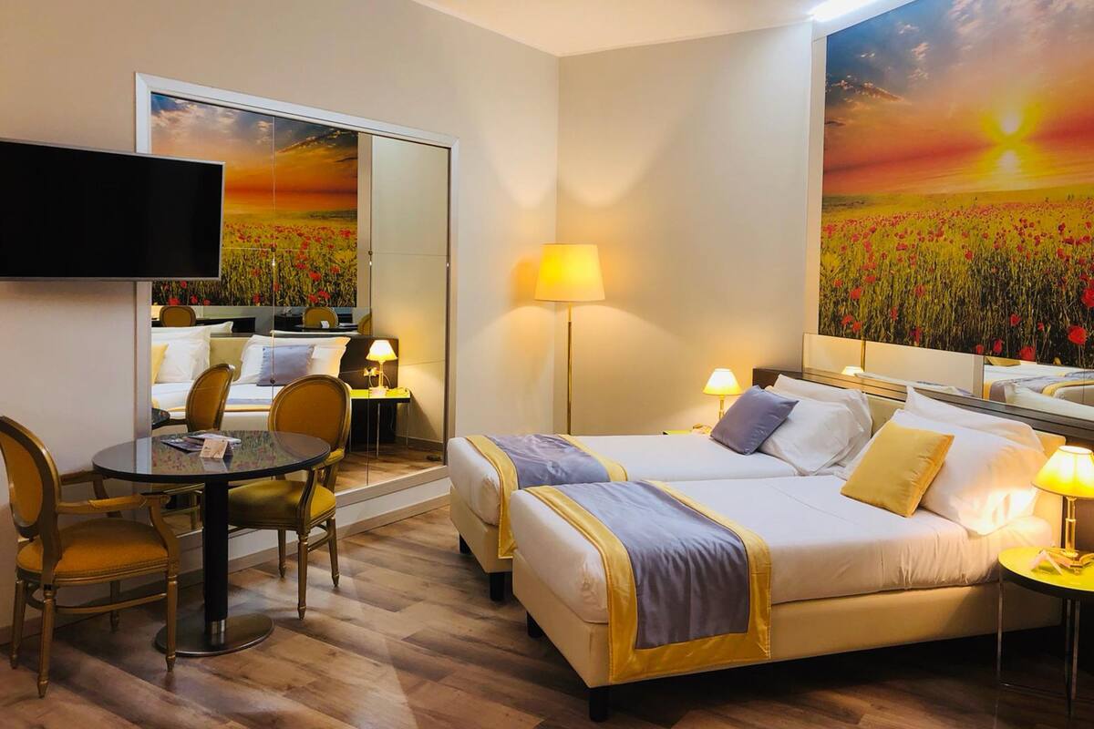 A hotel room with a bed, bedside table, lamp, chair, and a TV.