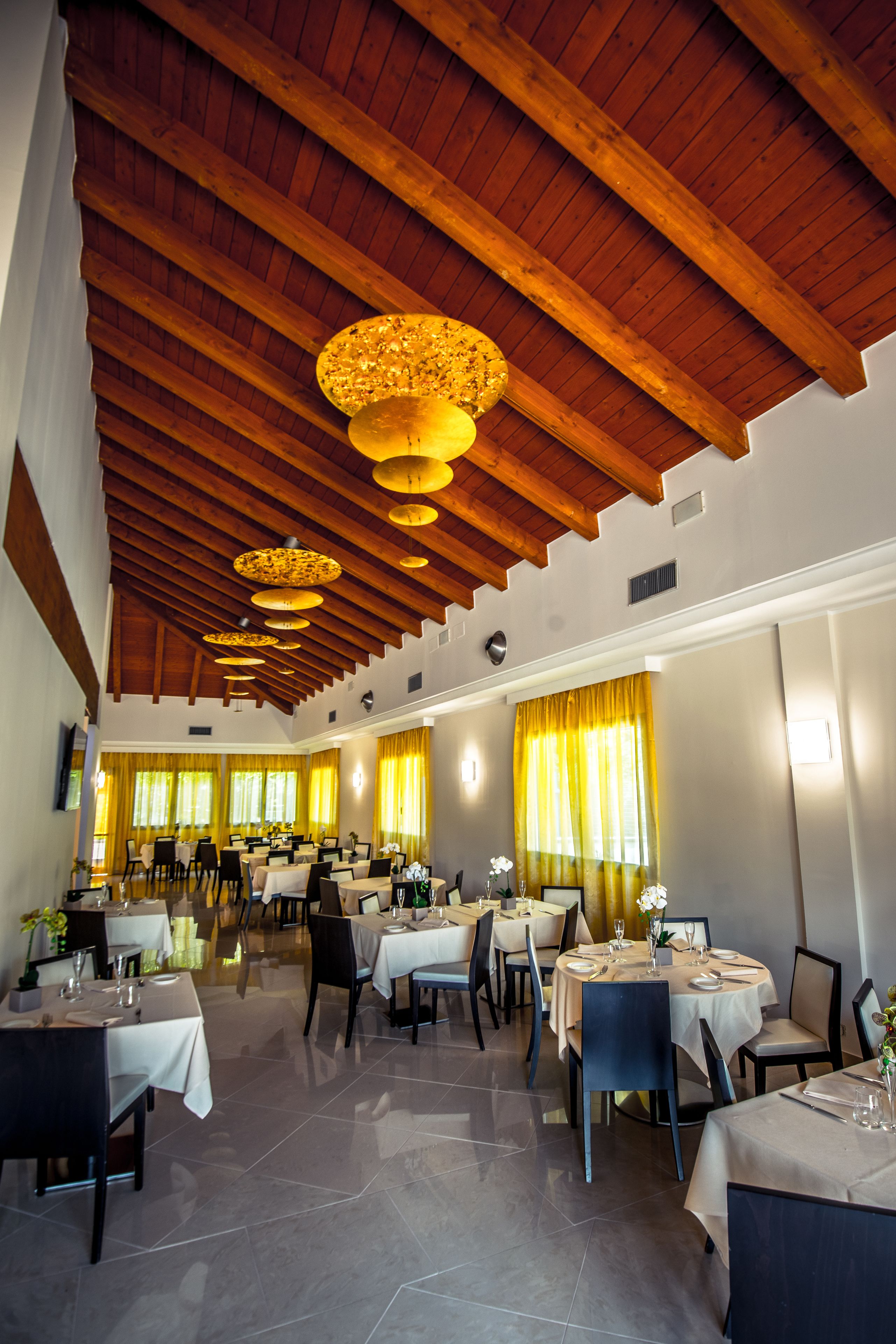 A spacious dining area with high wooden ceilings and multiple tables set for dining.