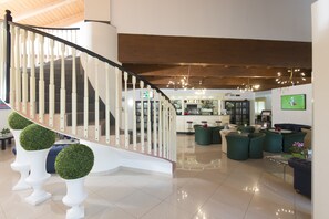A spacious lobby with a modern staircase, comfortable seating areas, and a bar. - AS Hotel Sempione Fiera (San Vittore Olona)