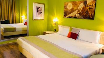Habitación de hotel con una cama grande, un espejo, un cuadro enmarcado y una lámpara de pared.