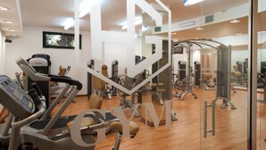 A gym with exercise equipment, mirrors, and a wooden floor.