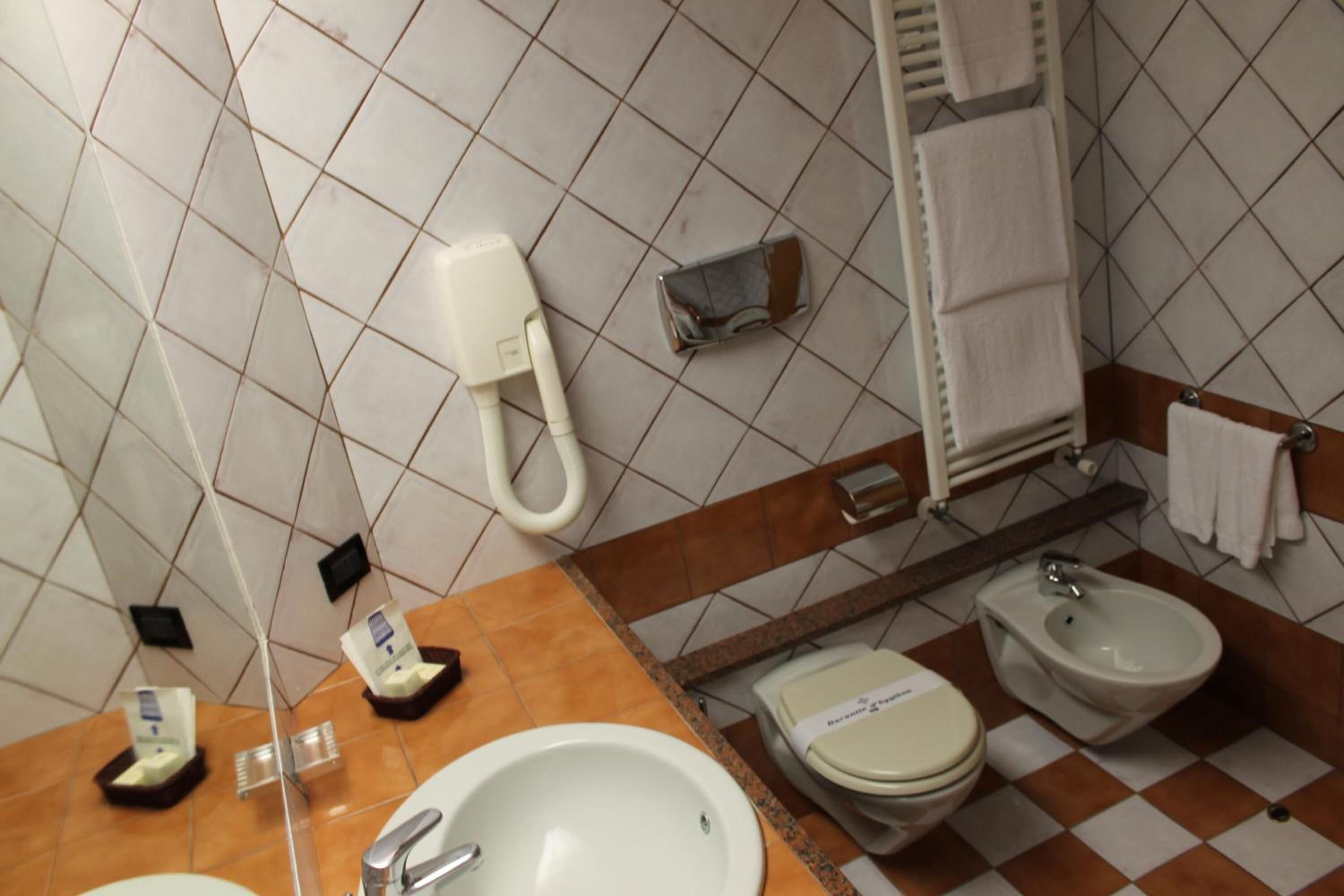 A bathroom with a sink, toilet, bidet, and towel rack.
