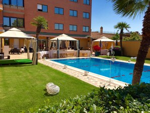 Una piscina al aire libre de temporada, sombrillas