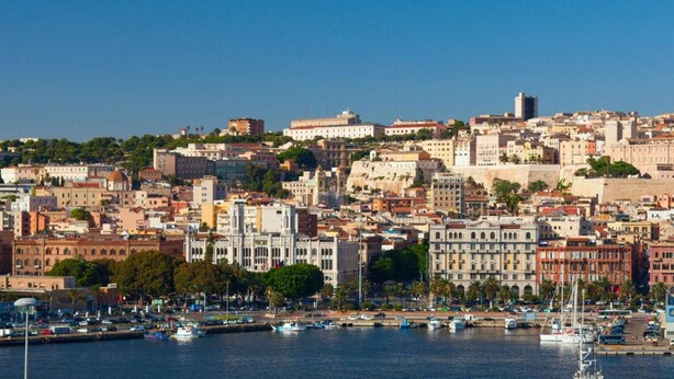 A coastal cityscape with historic buildings, a marina, and boats.