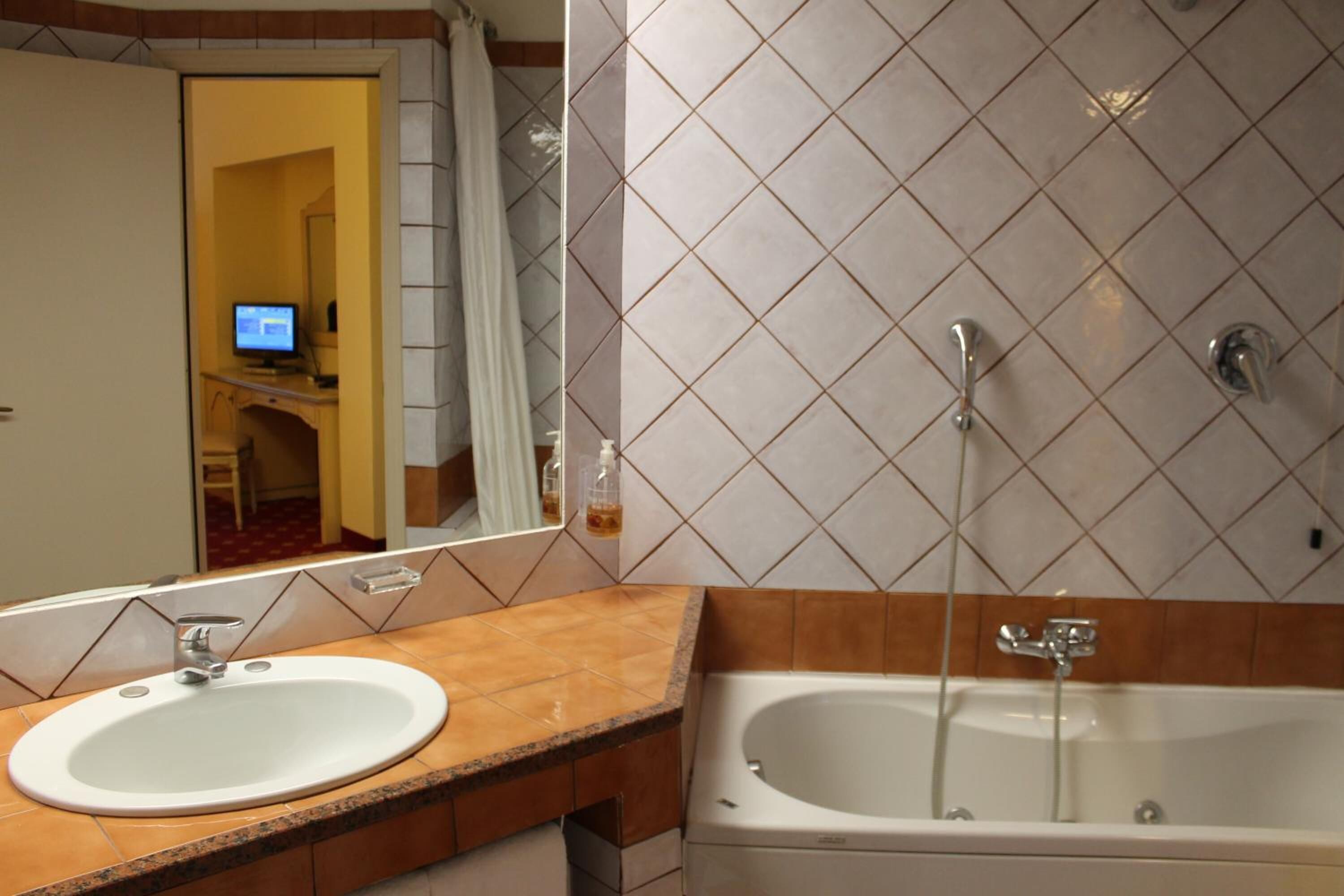 A bathroom with a sink, mirror, and bathtub.